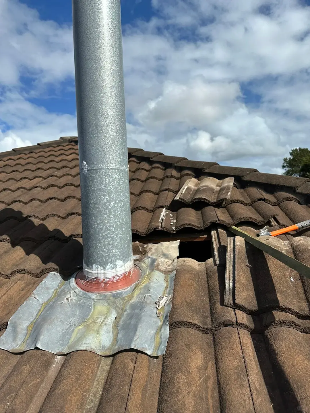 Concrete roof tiles removed around a metal flue penetration during leak investigation