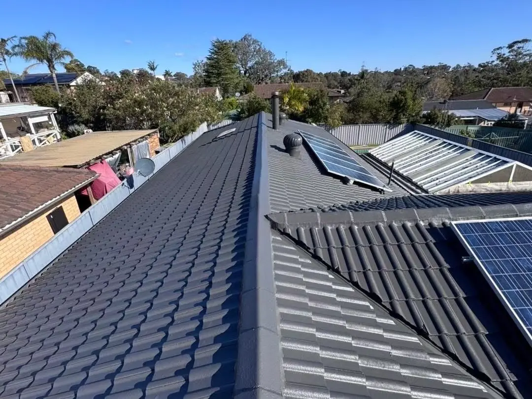Completed dark-grey concrete tile roof restoration viewed along the main ridge
